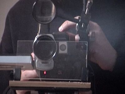 Film still from 'My Documentary Machine' (2026) by Jon Beaton. An old camcorder modified with a magnifying glass and a pepper's ghost rig.
